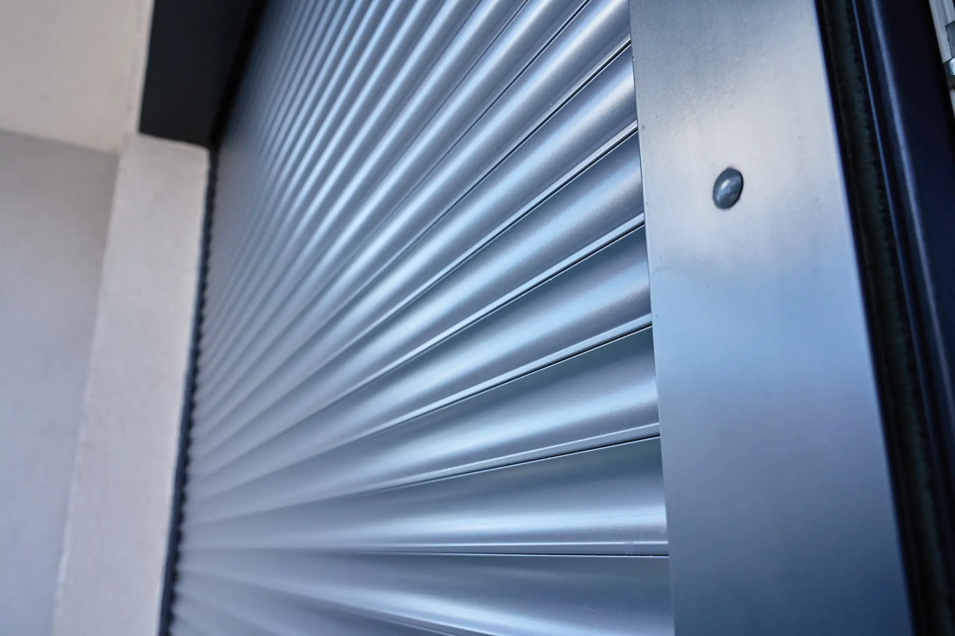 Automatic exterior roller shutter closing modern exterior window. Close up view of electric blind panel moving over glass surface. Concept of home security, privacy, sun protection