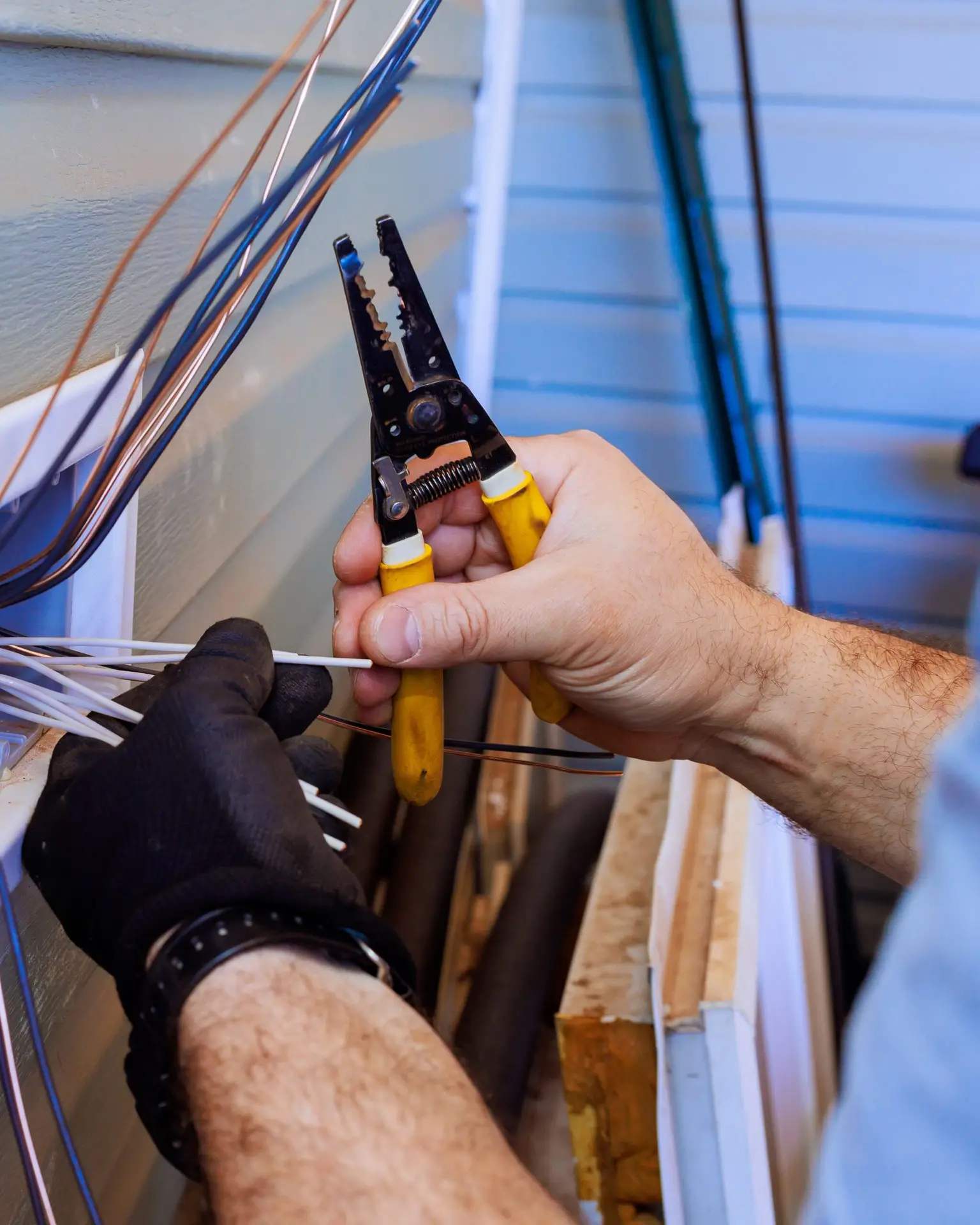 Expert technician working on electrical wiring near a residential home in a clear afternoon light